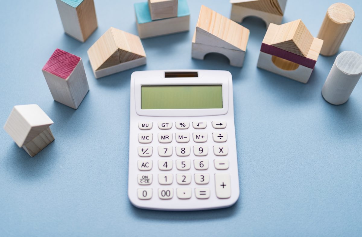 Calculator surrounded by small wooden building blocks representing financial modeling